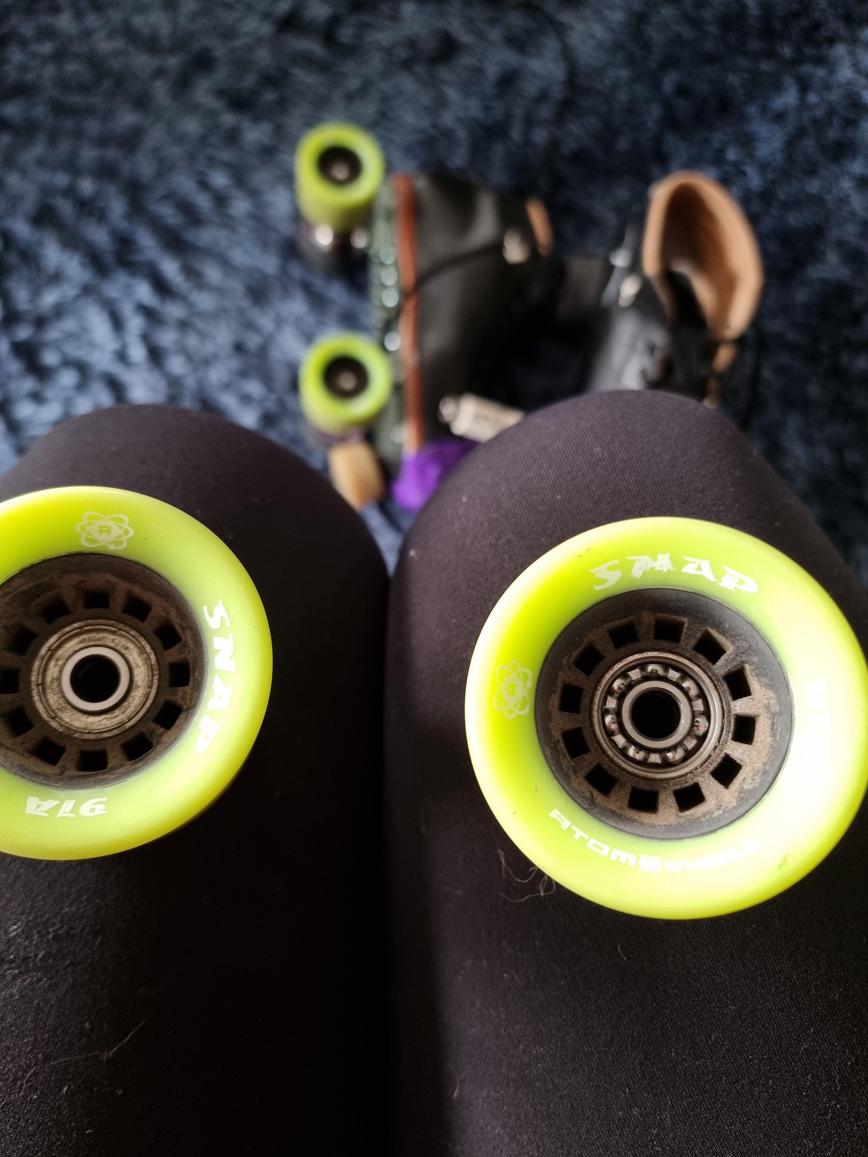 Roller skate wheels with bearings. One wheel has sealed bearings, the other wheel the ball bearings are visible, as the bearing shield is missing.